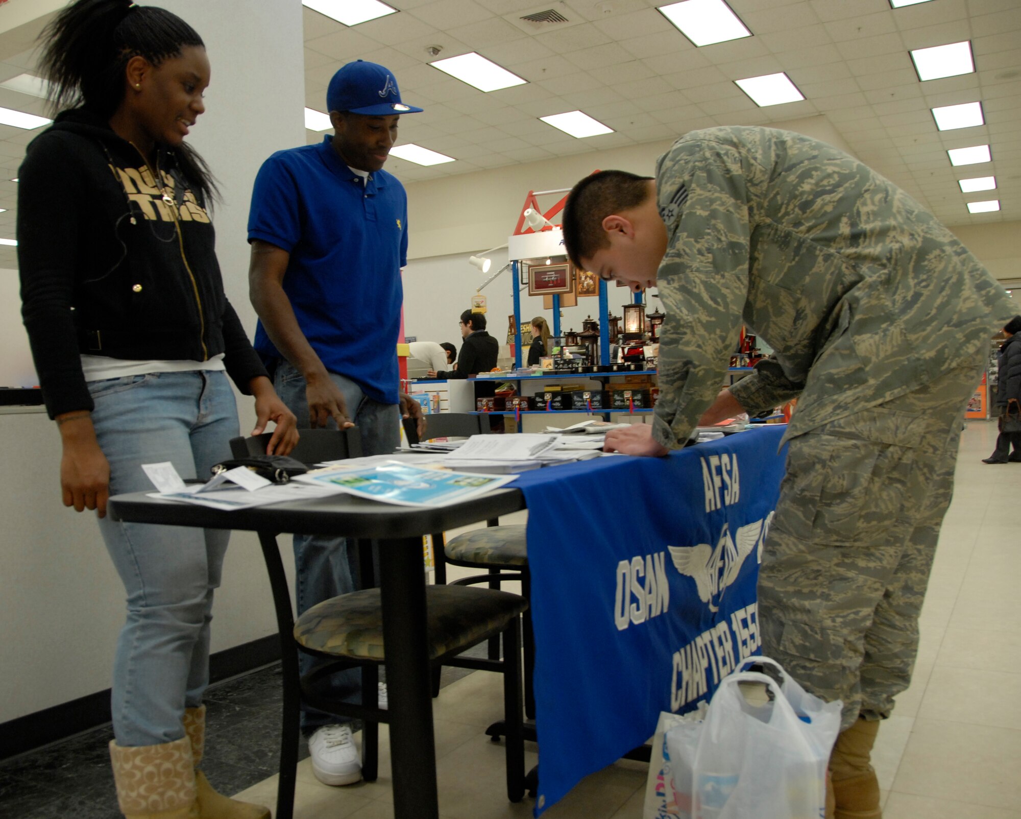 (Right) Senior Airman Shawn Erway, 51st Communications Squadron, signs up to become a member of the Osan Chapter of the Air Force Sergeants Association Feb. 6. (Left) Staff Sgt. Jewel Henderson, 51st Logistics Readiness Squadron, and Senior Airman Ronald Reeves, 51st CS, were among the AFSA members that hosted a membership drive at the Osan base exchange. More than 45 new members were added to Osan's AFSA, which puts the organization at more than 300 overall. For more information on AFSA, contact Master Sgt. Mysti Habetler at 784-2315. (U.S. Air Force Photo/1st Lt. Chris Hoyler)