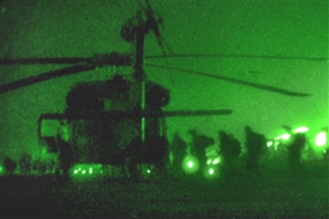 As seen through a night-vision device, U.S. Marines carry their gear out to Army helicopters before an air assault into Marja, Afghanistan, Feb. 13, 2010. UH-60 Black Hawk and CH-47F Chinook helicopters inserted nearly 300 Marines into the area.