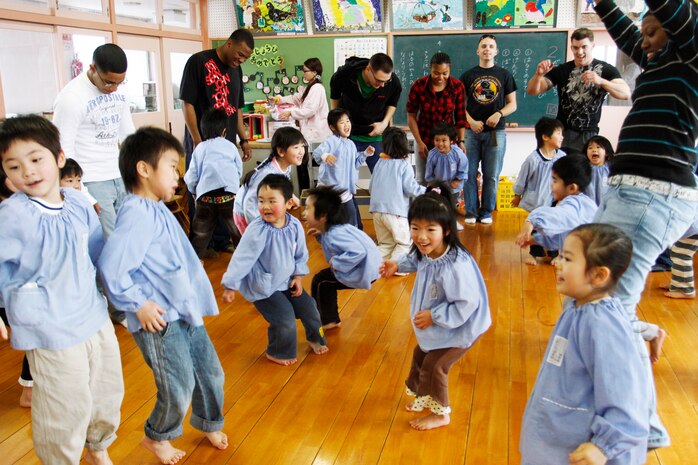 Station service members dance with the children of Marifu Hoikuen, a Kindergarten school in downtown Iwakuni, during a game designed to teach the children how to count in English, Feb. 18. When the music stopped, a number was yelled out and everyone needed to gather in groups with the number of people equaling the number that was called out.