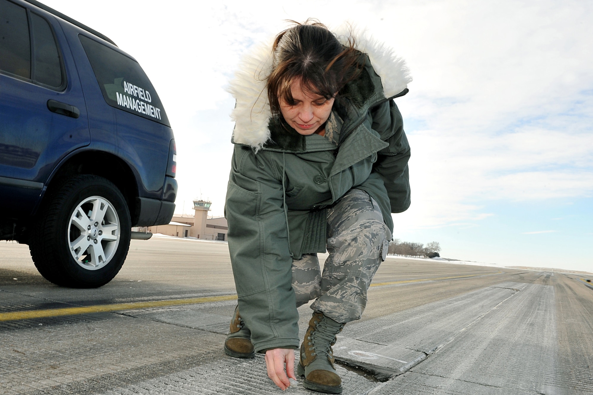 OFFUTT AIR FORCE BASE, Neb. - Senior Master Sgt. Laura Liedke, airfield manager with the 55th Operations Support Squadron, picks up a piece of foreign object debris on a taxiway here Feb. 16. The Airfield Operations Flight airfield management team coordinates with various base agencies to provide a safe environment for aircraft operations. 
 
U.S. Air Force photo by Charles Haymond