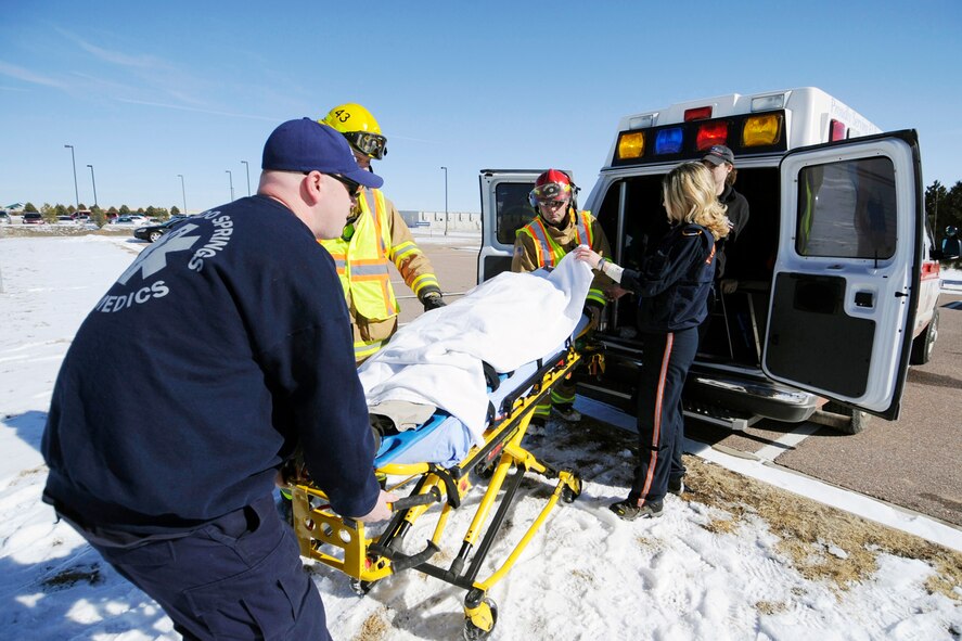 Base emergency services members move a "shooting victim" from an ambulance with the assistance of paramedics from the Flight for Life Colorado crew during an exercise Feb. 10, 2010, at Schriever Air Force Base, Colo.  The exercise scenario was conducted with the assistance of a civilian helicopter and crew to add realism.  (U.S. Air Force photo/Dennis Rogers)