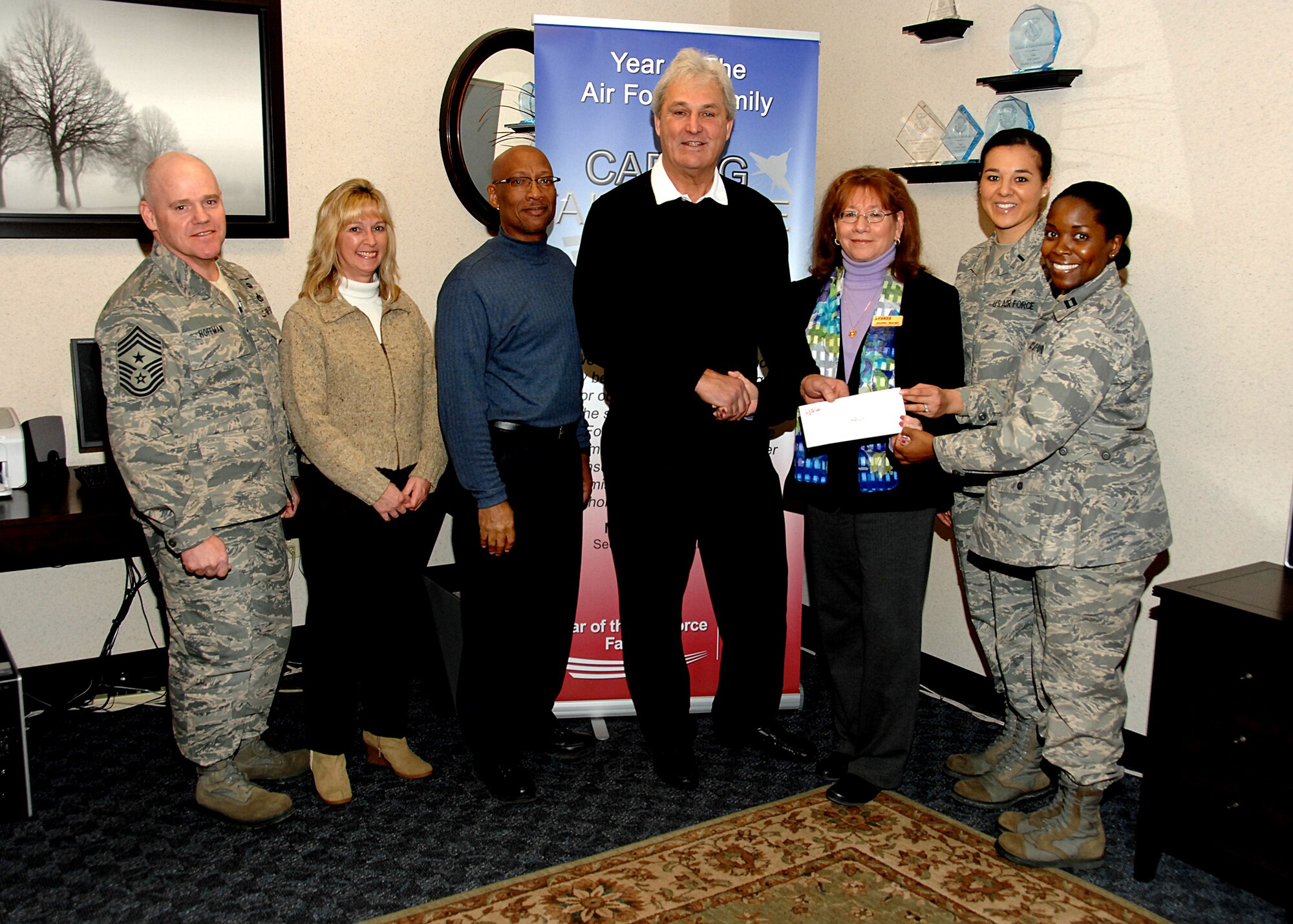 Mr. John Marks, coach of the Dayton Gems Hockey team (Center) hands a check in the amount of $3,000 to Jennifer Spurgin (right of Mr. Marks), from the 88th Force Support Squadron's flight chief for the Airman & Family Service Flight, 1st Lt. Cynthia Newberry, resource management intern and Capt. Janelle Quinn, Air Force Assist Fund installation project officer.  To the left of Mr. Marks is Alvin Dennis, community readiness technician, Jill Sanders, Dayton Gems public relations manager and Chief John Hoffman, 88th Air Base Wing command chief. (U.S. Air Force photo by Ben Strasser)