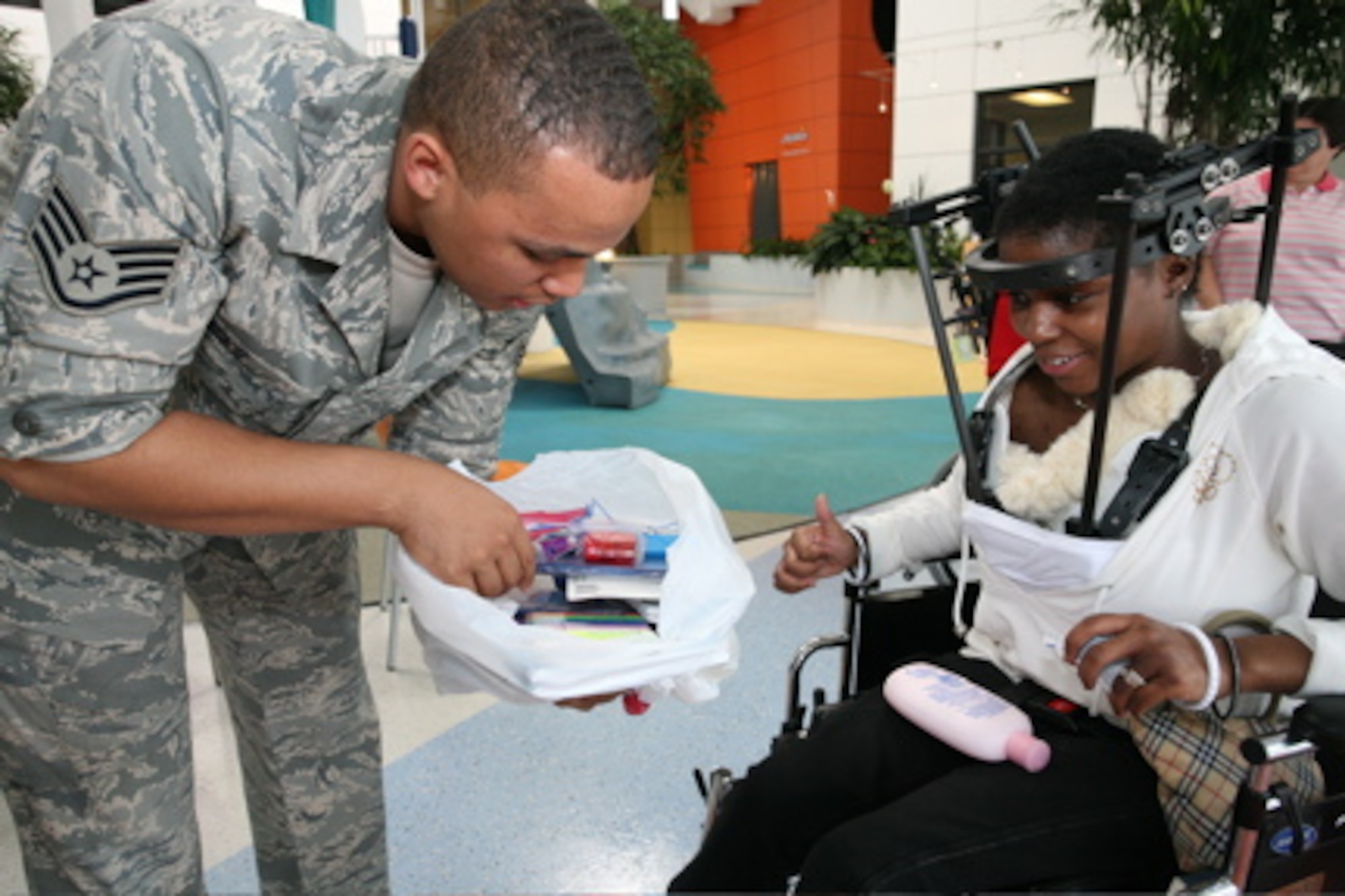 Staff Sgt. Jewell Hicks, 13th Intelligence Squadron imagery analyst, hands out toys to a child at a medical facility as part of Airmen for Children. Sergeant Hicks established the program to fullfill a childhood promise of volunteering to help children who suffer from diseases and illnesses. (Courtesy Photo)