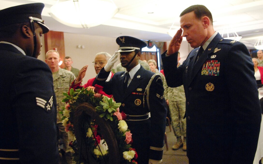 The last surviving original Tuskegee Pilot, retired Lt. Col. Charles Mcgee, center in red, looks on as honor guardsman Airman 1st Class Travis Kidd places a wreath in honor of the Tuskegee Airmen’s recently deceased ace pilot, Lt. Col. Lee Archer. 316th Wing Commander, Col. Steven Shepro, right, hosted the Feb. 16, luncheon honoring Lieutenant Colonel Archer and the accomplishments of the Tuskegee Airmen. (U.S. Air Force Photo by Staff Sgt. Corenthia Fennell)

