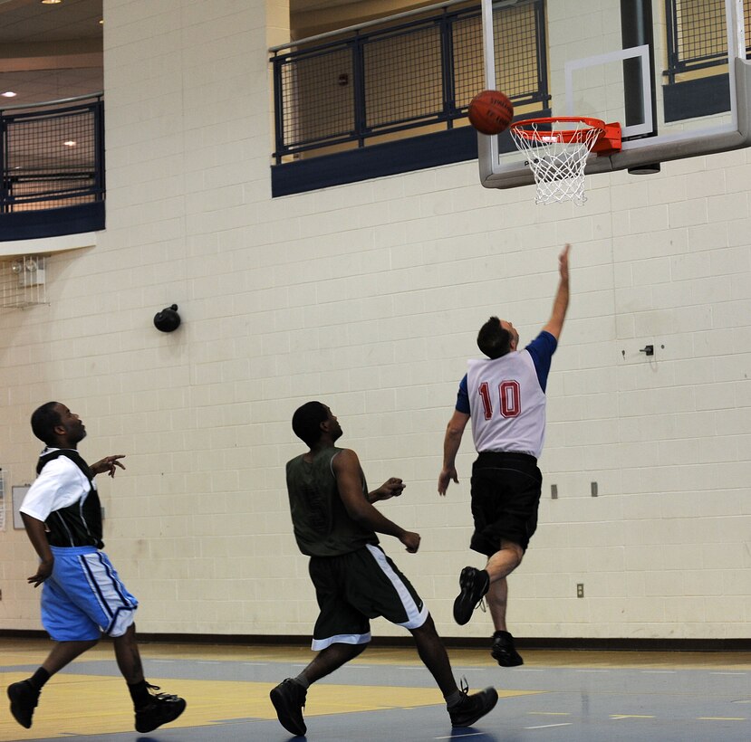 LANGLEY AIR FORCE BASE, Va. -- Air Combat Command/A-1 Forward Fredrick Cooper bypasses two Ryan Center defenders for a lay-up Feb. 17 at the Shellbank Fitness Center. It was a close game for the Over 30 basketball league teams, but ACC/A-1 upset the Ryan Center by one point, 47-46.  (U.S. Air Force photo/Senior Airman Zachary Wolf) 