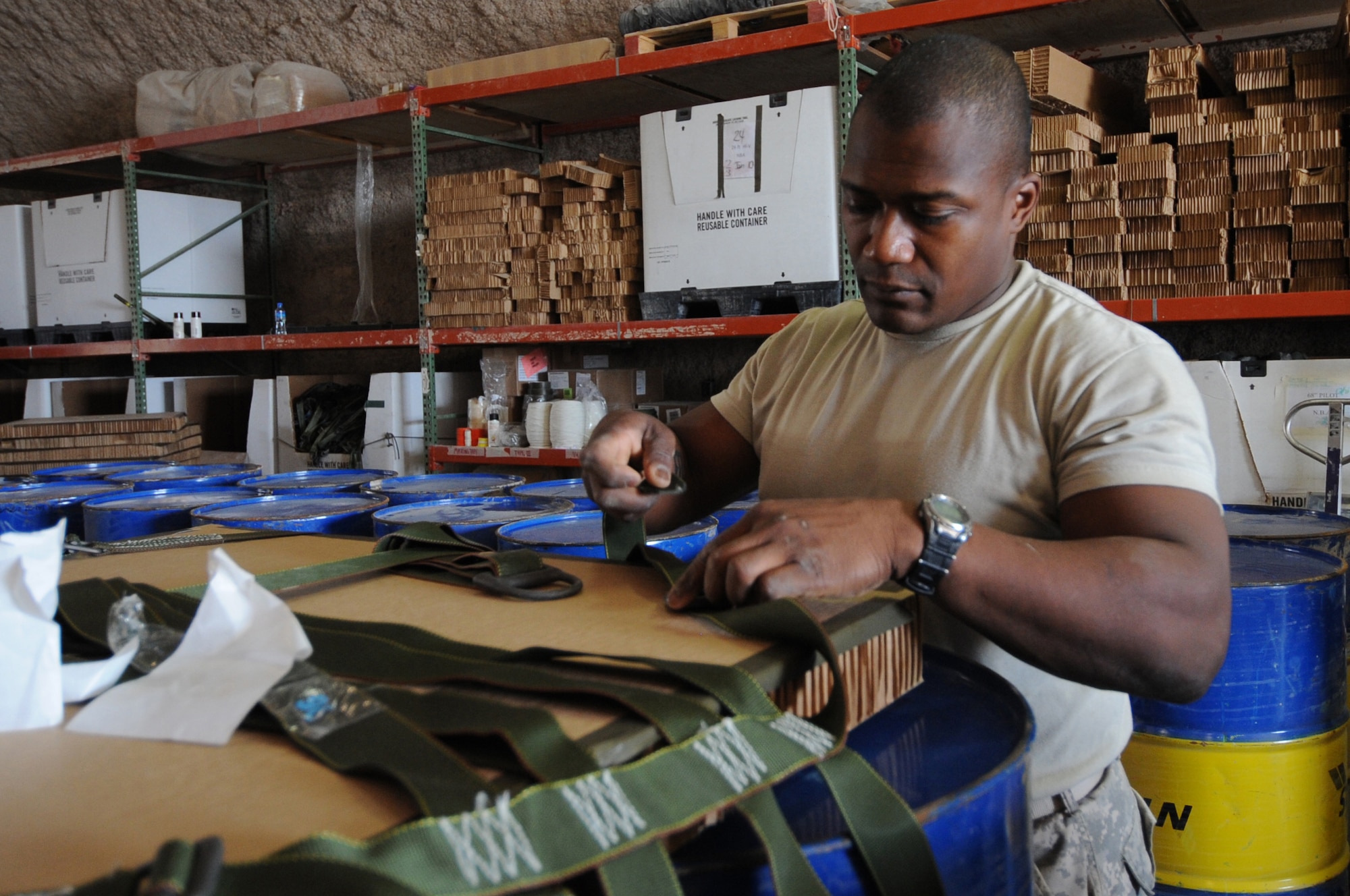 Army Spc.Cleveland Spain, 824th Riggers parachute rigger, ties down a strap on an airdrop mission container delivery system's sling assembly at a non-disclosed Southwest Asia location, Feb 16, 2010. (U.S. Air Force photo byTech. Sgt. Michelle Larche)[RELEASED]
