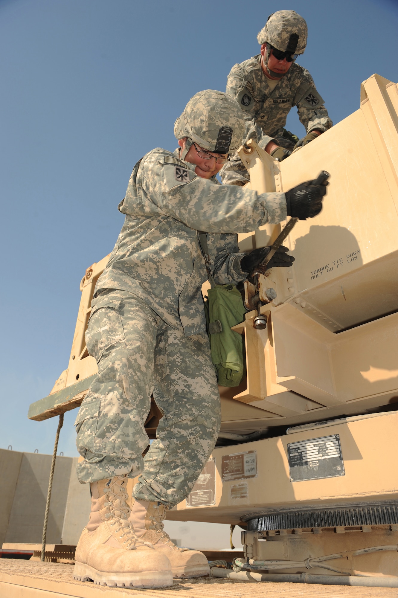 Army Staff Sgt. James Huntington, Bravo Battery, 1-43 Air Defense Artiller,y Patriot Launch Station operator/maintainer, unhooks canister beam chains from a missile canister as Spc. Alarick Garza, Bravo Battery, 1-43 ADA, Patriot Launch Station operator/maintainer, torques the canister onto a Patriot missle launcher during a guided-missile transporter reload certification activity at a non-disclosed Southwest Asia location, Feb. 12, 2010. (U.S. Air Force photo by Tech. Sgt. Michelle Larche)[RELEASED]