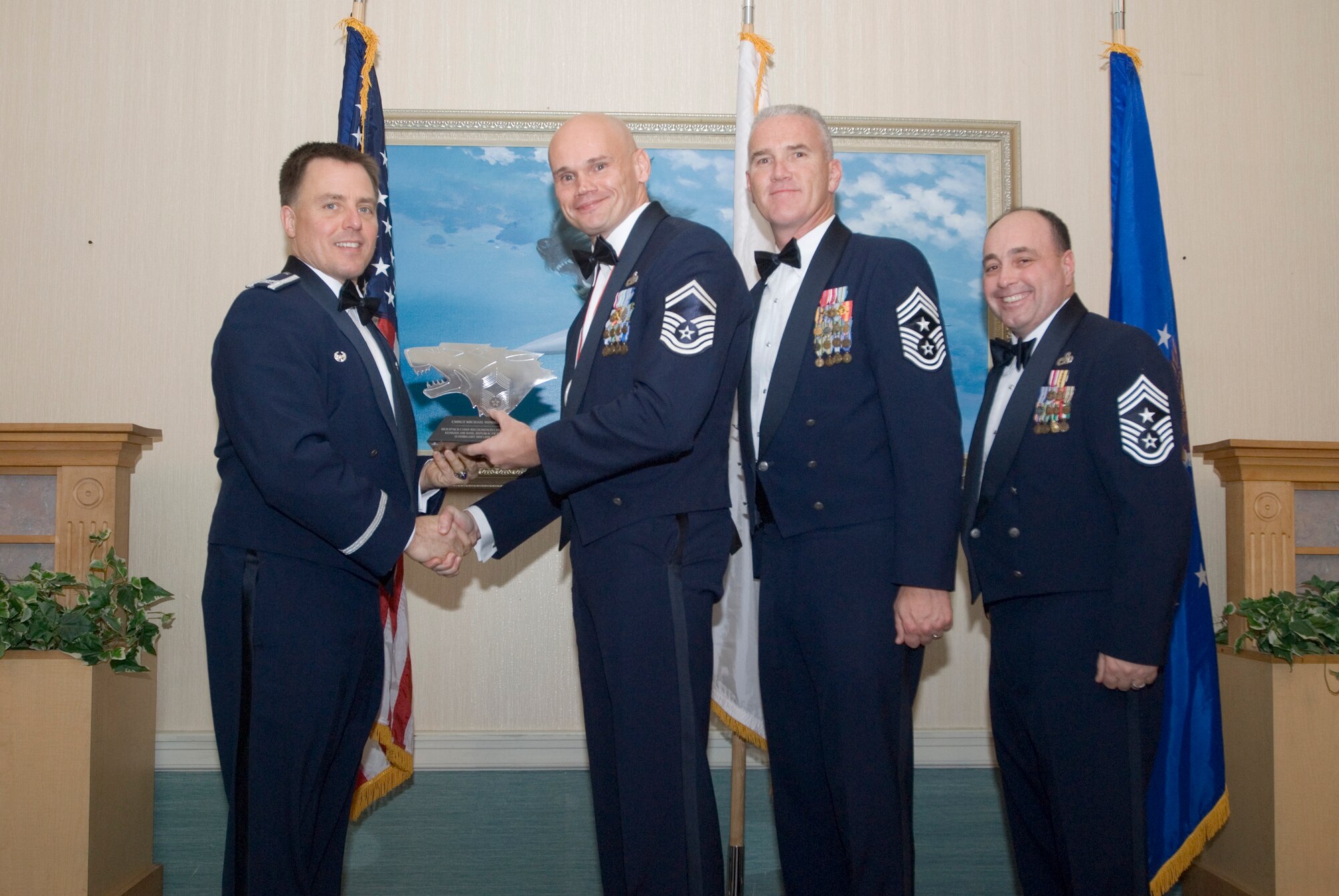 KUNSAN AIR BASE, Republic of Korea- (left to rt.) Col. Robert Givens presents a plaque to Senior Master Sgt. Michael Winslow, along with Command Chief Master Sgt. Brooke McLean, PACAF, and Command Chief Master Sgt. James Sanders, 8th FW, during the chief master sergeant induction ceremony, here, Feb. 13. The purpose of the induction ceremony was to celebrate and recognize the four new chiefs being promoted in the Wolf Pack. (U.S. Air Force photo/Senior Airman Jonathan Steffen)

