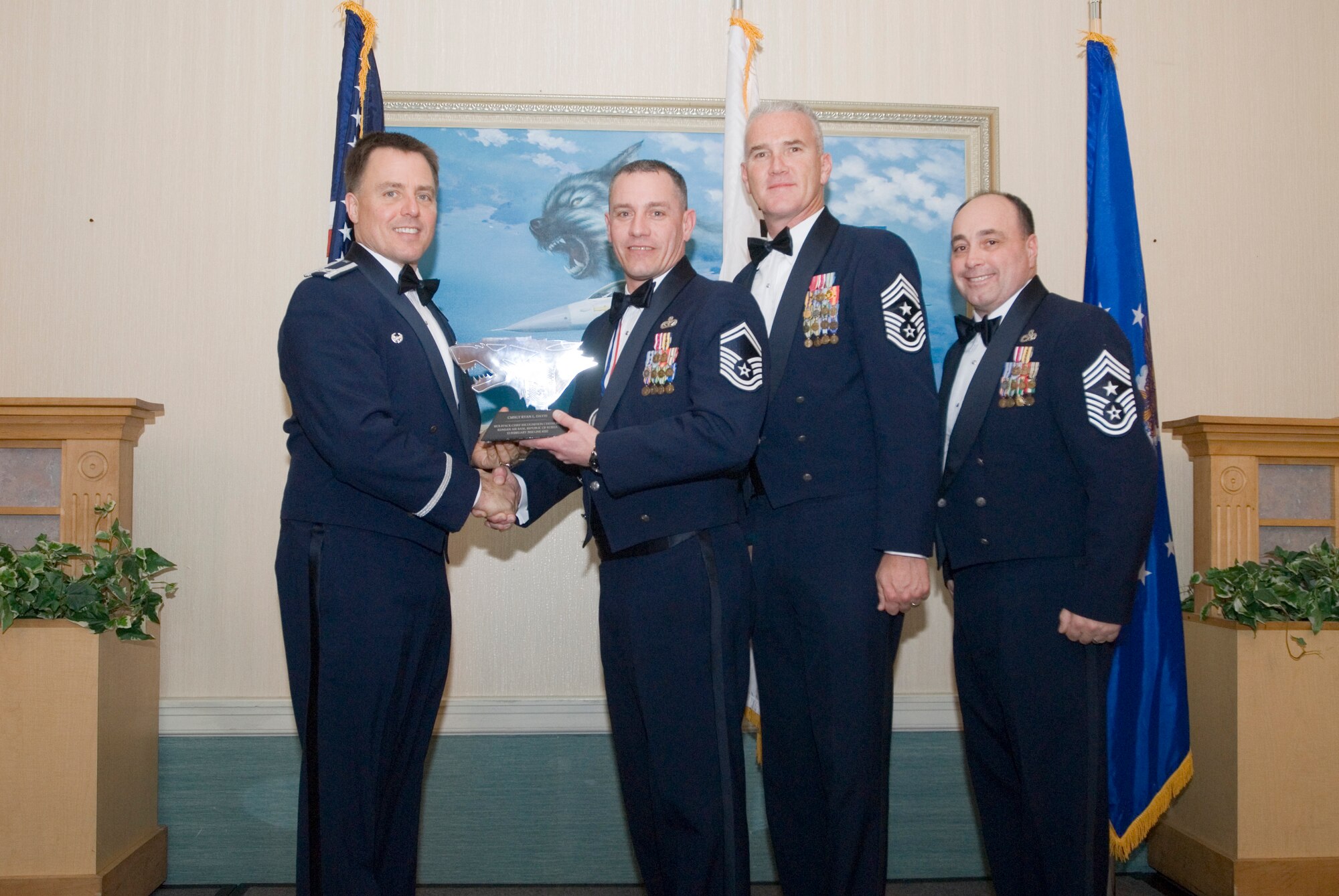 KUNSAN AIR BASE, Republic of Korea- (left to rt.) Col. Robert Givens presents a plaque to Senior Master Sgt. Ryan Davis, along with Command Chief Master Sgt. Brooke McLean, PACAF, and Command Chief Master Sgt. James Sanders, 8th FW, during the chief master sergeant induction ceremony, here, Feb. 13. The purpose of the induction ceremony was to celebrate and recognize the four new chiefs being promoted in the Wolf Pack. (U.S. Air Force photo/Senior Airman Jonathan Steffen)
