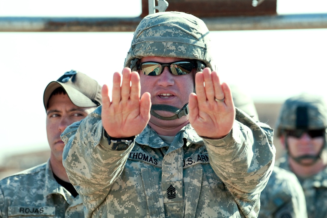 U.S. Army 1st Sgt. Scott Thomas rehearses the commands he will give to paratroopers as a jumpmaster as Staff Sgt. Timothy Rojas, jumpmaster instructor from Fort Bragg’s Advanced Airborne School, looks on, Al Asad Airbase, Iraq, Feb. 7, 2010. Thomas assigned to the 82nd Airborne Division's Company C, 1st Battalion, 504th Parachute Infantry Regiment, 1st Brigade, Advise and Assist Brigade, is preparing for training parachute jumps in Iraq later the same month.