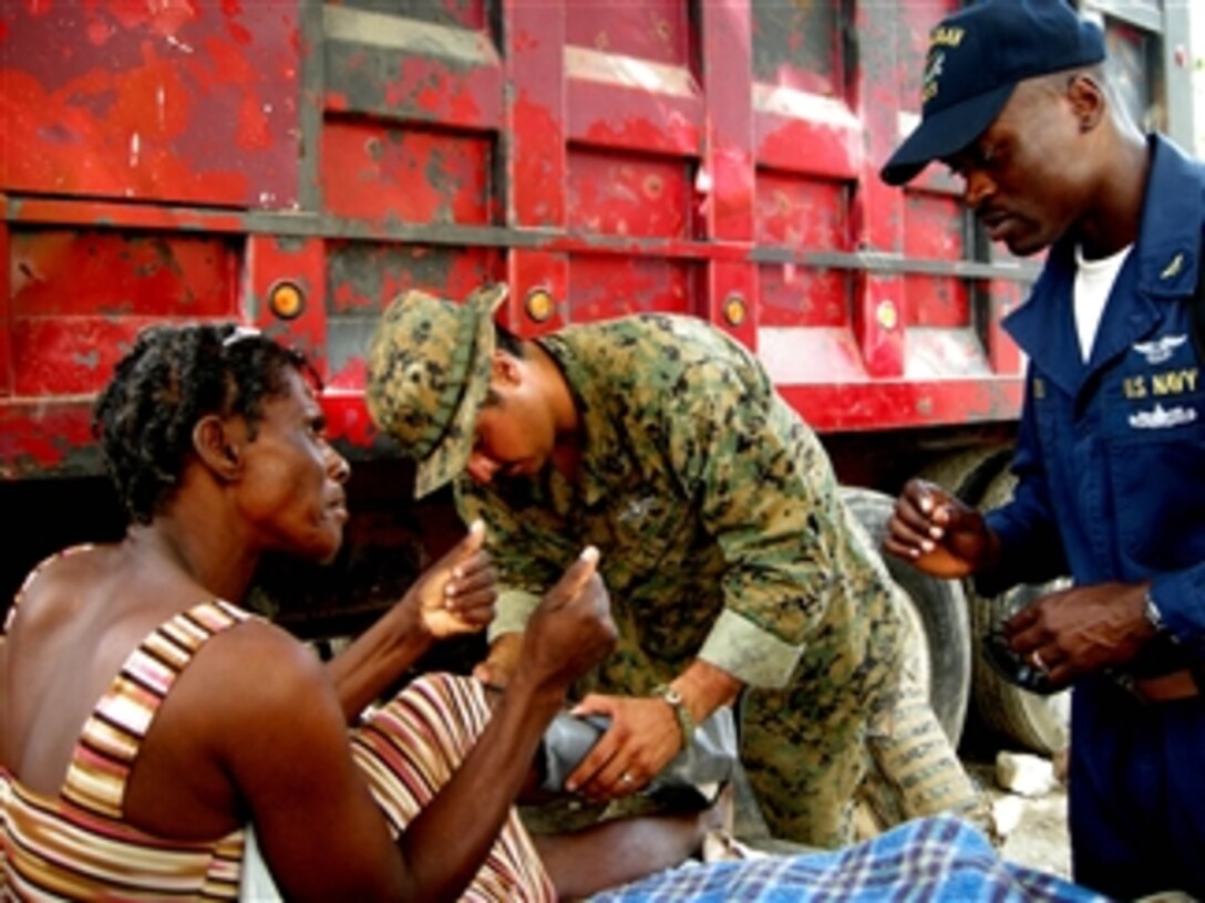 U.S. Navy Petty Officer 3rd Class Philip Davila, a hospital corpsman assigned to the 22nd Marine Expeditionary Unit, examines a Haitian woman's leg as Chief Warrant Officer Wilfrid Bossous translates in Grand Goave, Haiti, on Feb. 4, 2010.  The sailors are embarked aboard the multipurpose amphibious assault ship USS Bataan (LHD 5).  The Bataan is conducting humanitarian and disaster relief operations as part of Operation Unified Response.  