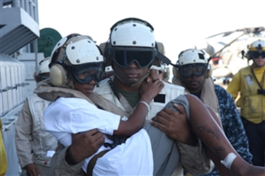 U.S. Marine Corps Sgt. Jarrell Williams, a platoon sergeant with Combat Cargo, 24th Marine Expeditionary Unit, carries 14-year-old Lydie Augustin across the flight deck aboard the amphibious assault ship USS Nassau (LHA 4) and into an MV-22 Osprey tilt-rotor aircraft from Marine Medium Tilt Rotor Squadron 162 which flew her back to Grande Saliene, Haiti, to be reunited with her family and friends on Feb. 1, 2010.  Augustin was brought aboard the ship the week before to receive emergency medical care for wounds received during the Jan. 12, 2010, earthquake in Haiti.  