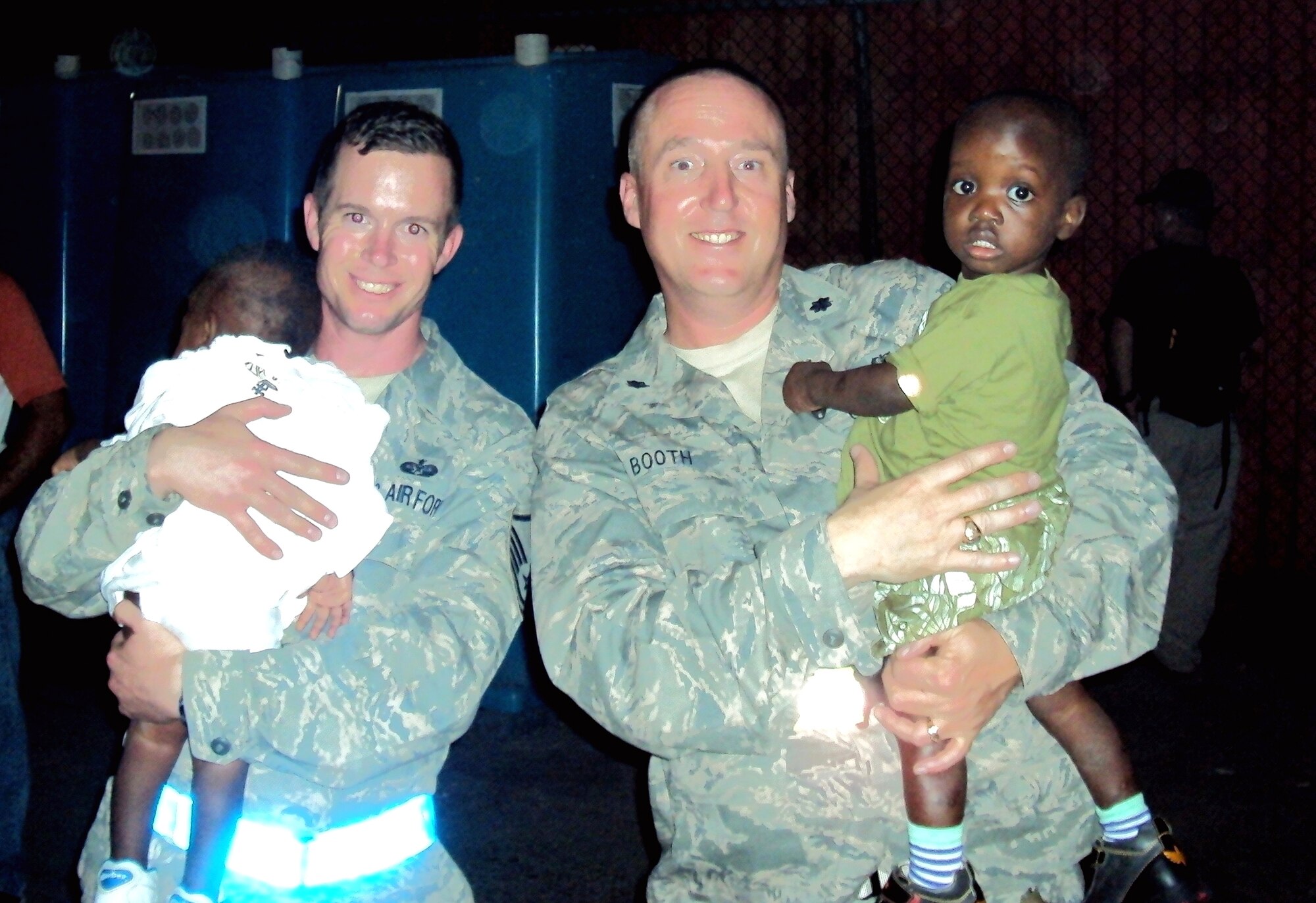 MOUNTAIN HOME AIR FORCE, Idaho – 24th Air Expeditionary Group staff judge advocate Lt. Col. Robert Booth and Master Sgt. Jerol Boyce each hold a Haitian child while deployed to Haiti. (Courtesy photo)
