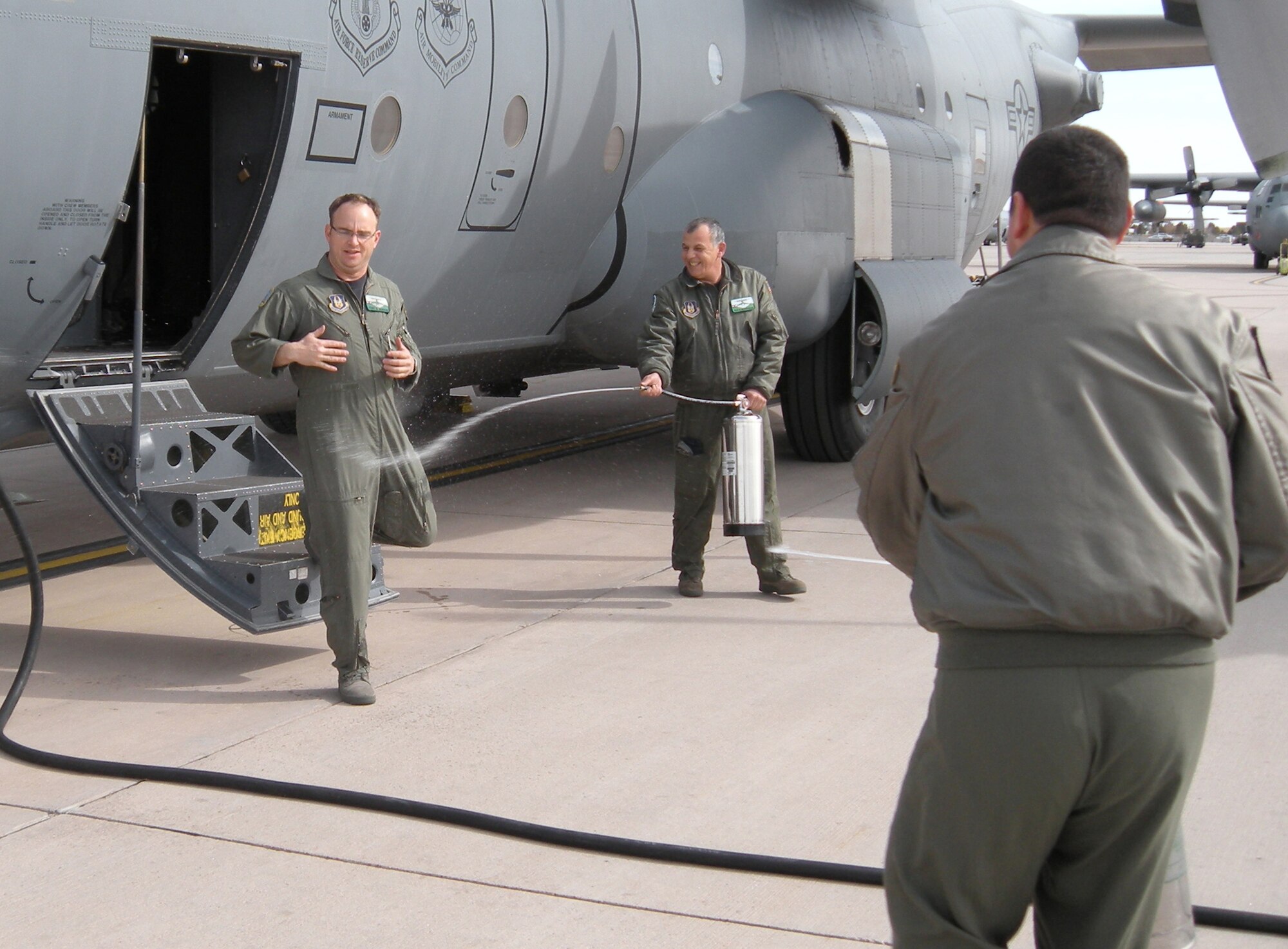 Tech.  Sgt. Scott Gordon (left) unsuspectingly walks into streams of water Feb. 18 while members of his squadron douse him at Peterson Air Force Base, Colo. Sergeant Gordon, a loadmaster with the Air Force Reserve's 302nd Airlift Wing, flew his last C-130 Hercules mission with the wing's 731st Airlift Squadron before taking an Air Reserve Technician position with the 301st Fighter Wing in Ft. Worth, Texas. It is a tradition for Air Force aircrew members to water down their fellow Airmen after a member's final flight with their unit. (U.S. Air Force photo/Master Sgt. Mark Skarban)