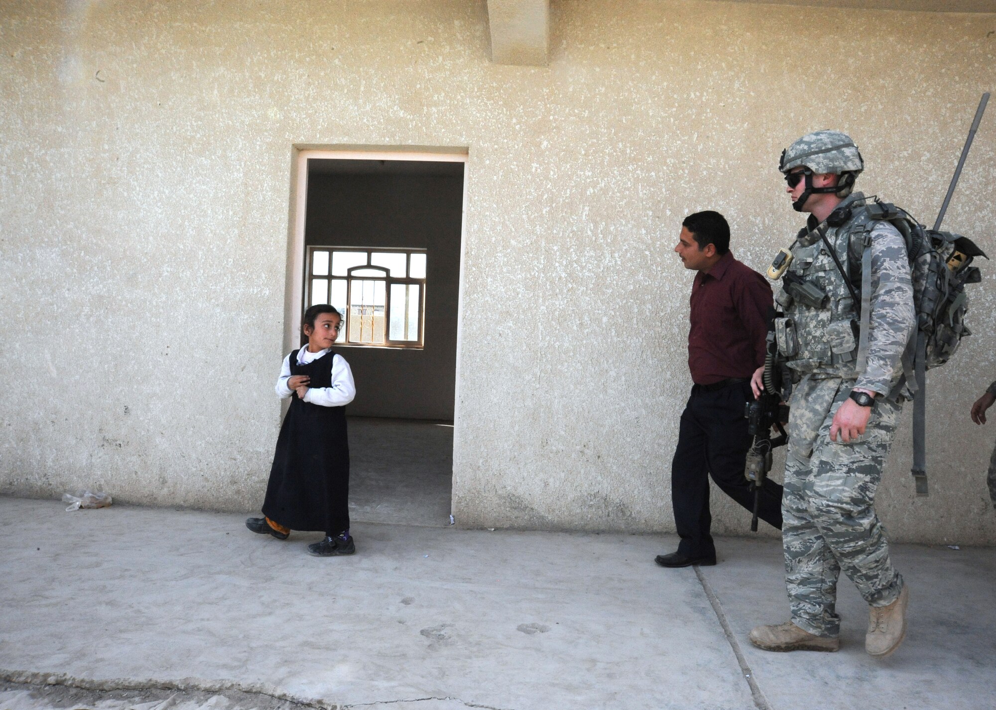 Air Force Staff Sgt. Jared Winker, 732nd Expeditionary Security Forces Squadron Detachment 3, walks through a polling station providing an assessment while being watched by a young Iraqi girl Feb 15, 2010.  The purpose of these assessments is to build a rapport between U.S. Forces and the Iraqi police, while providing key insights to force protection at polling sites for the March 7, elections. (U.S. Air Force photo/Master Sgt. Trish Bunting/Released)