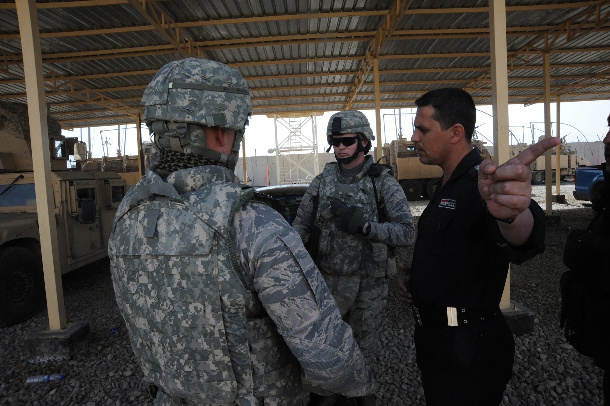 Air Force Tech. Sgt. Dennis Kuzel (left) and Staff Sgt. Jared Winker, 732nd Expeditionary Security Forces Squadron Detachment 3, speak with an Iraqi police officer before conducting a joint polling station assessment Feb 15, 2010.  The purpose of these assessments is to build a rapport between U.S. Forces and the Iraqi police, while providing key insights to force protection at polling sites for the March 7, elections. (U.S. Air Force photo/Master Sgt. Trish Bunting/Released)