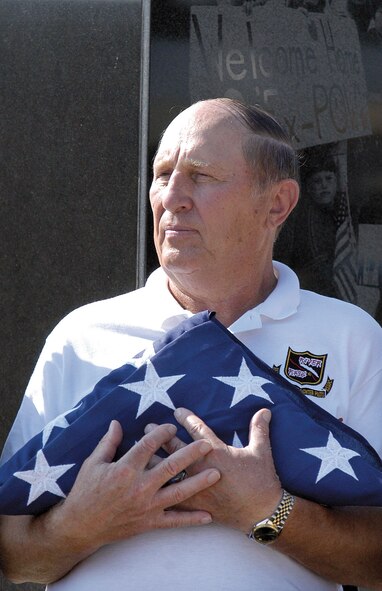 After speaking during a 2007 POW/MIA event at the memorial in the Tinker air park, retired Air Force Col. Leroy Stutz cradles a flag given to him. After being shot down during the Vietnam War, he was held as a prisoner of war for six years and recently spoke to the Airman Leadership School graduating class about his experiences. (Air Force photo by Margo Wright)