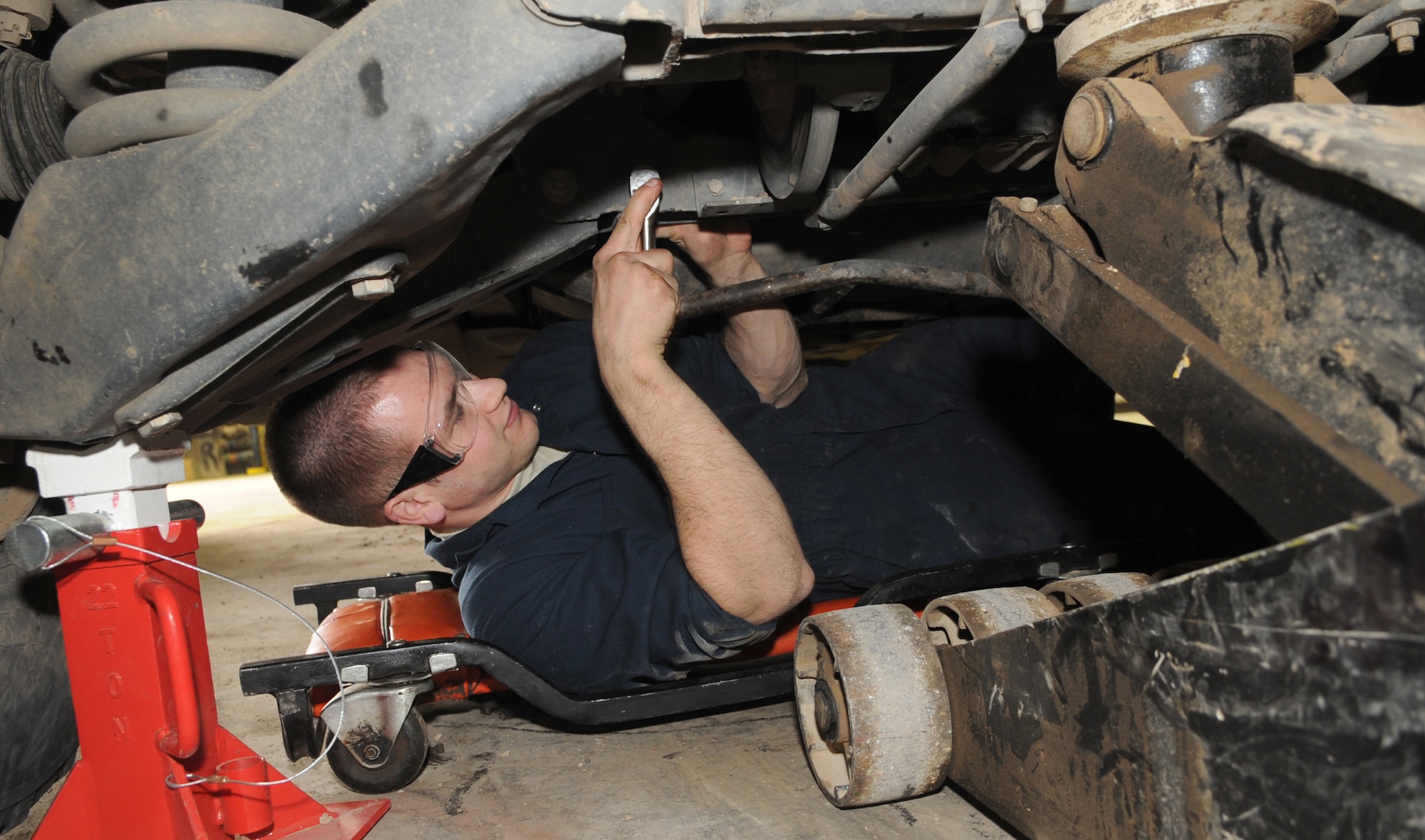 KIRKUK REGIONAL AIR BASE, Iraq –A1C Lelan Larroqe, 506th Expeditionary Logistics Readiness Squadron vehicle maintainer, works on a High Mobility Multi-purpose Wheeled Vehicle Feb. 12, 2010.  Airmen Larroqe is removing the armor from the bottom of the vehicle in order replace the power steering pump. The vehicle maintenance shop has a hand in repairing just about any mission essential vehicle on base, including HMMWVs, forklifts, cargo loaders, dodge pickups, ambulances and fire trucks.  (U.S. Air Force photo/Staff Sgt. Tabitha Kuykendall)	    