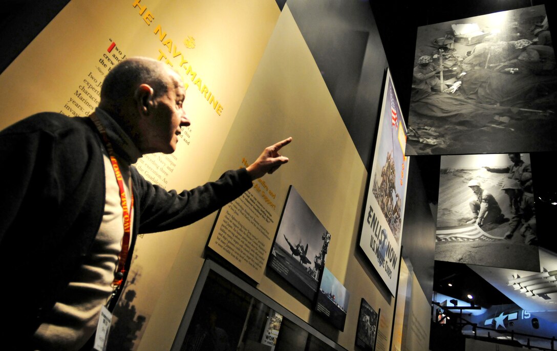 Greg "Doc" Emery points to a photo hanging in which he is shown giving aid to a wounded Marine on the beaches of Iwo Jima during the ceremony commemorating the 65th Anniversary of the Battle of Iwo Jima at the National Museum of the Marine Corps, Triangle, VA, Feb. 19, 2010.