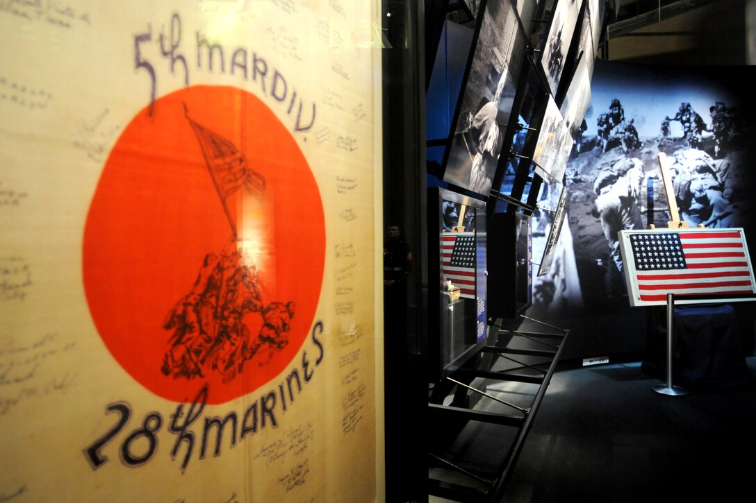 A guidon displaying 5th MARDIV, Marine Division, 28th Marines is displayed in the foreground. The U.S. Flag incased in the background was the first flag raised by U.S. Marines on Mt. Suribachi, Iwo Jima, Feb. 23, 1945. The National Museum of the Marine Corps, Triangle, VA, Feb. 19, 2010.