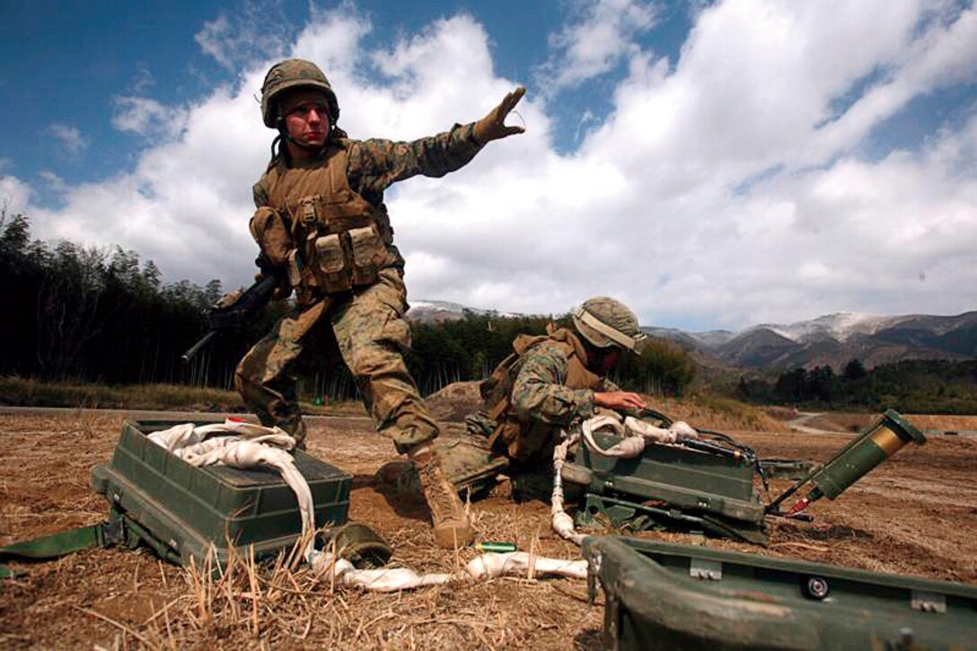 Lance Cpls. Ryan N. Woolman, left, and Bobby Hanesana, both combat engineers with Combat Engineer Company, Combat Assault Battalion, 3rd Marine Regiment, 3rd Marine Division, III Marine Expeditionary Force, prepare to take cover after setting up an anti-personnel obstacle breaching system at Nihonbara Training Area, Japan, Feb. 20.