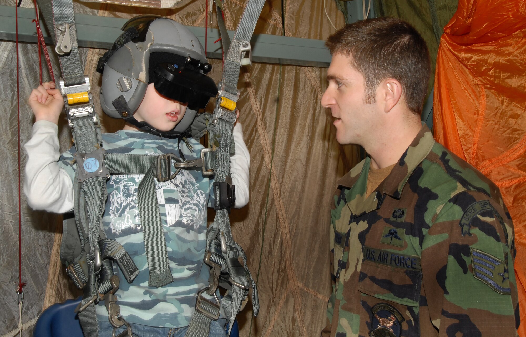 Maxwell Eckenrode, son of Staff Sgt. Jason Eckenrode of the 18th Operations Support Squadron, tries out the 31st Rescue Squadron's parachute simulator with the help of Staff Sgt. Justin Watters, 353rd Operations Support Squadron survival, escape, resistance and evasion specialist, during Rescue Fest Feb. 20. 