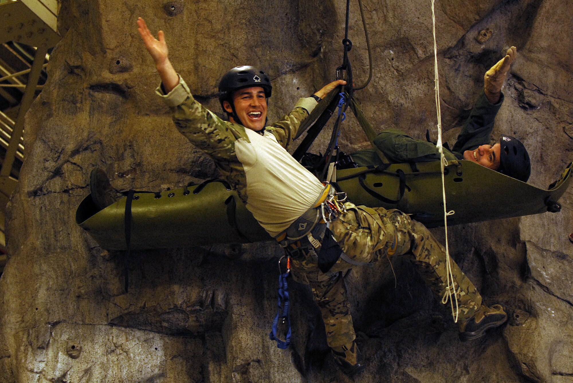A pararescuemen from the 31st Rescue Squadron rappels down a rock climbing wall while recovering Col. Lenny Richoux, 18th Wing deputy commander and simulated victim, during Rescue Fest Feb. 20. Airmen from the unit held several demonstrations on how they rappel into areas, how they recover victims from mountainous terrain, and how to survive when stuck behind enemy lines. (U.S. Air Force photo/Staff Sgt. Jason Lake)