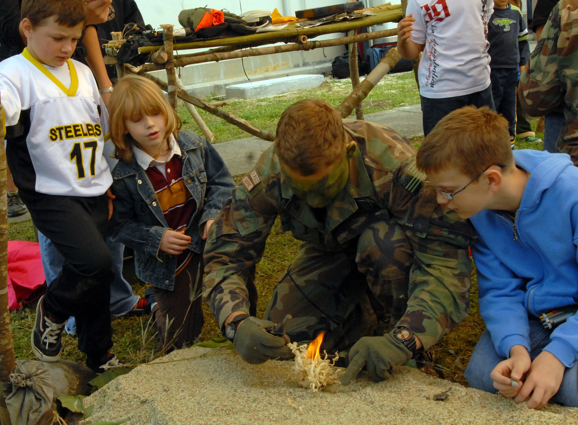Tech. Sgt. Trevor Brinton, a 31st Rescue Squadron survival, escape, resistance and evasion specialist, shows children how to start a fire using flint and bamboo shavings during Rescue Fest Feb. 20. (U.S. Air Force photo/Staff Sgt. Jason Lake)