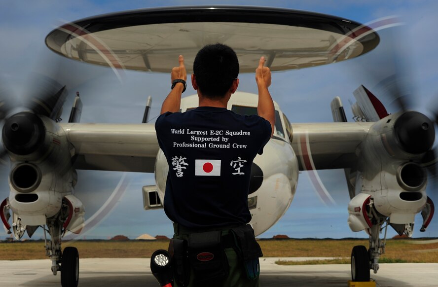 An E-2C Hawkeye aircraft crew chief from 601st Squadron, Airborne Early Warning Group, Misawa Air Base, Japan, directs an E-2C into an aircraft parking spot at Andersen Air Force Base, Guam, during Exercise Cope North, Feb. 18, 2010. The United States Air Force and the Japan Air Self-Defense Force conduct Cope North annually at Andersen Air Force Base to increase combat readiness and interoperability, concentrating on coordination and evaluation of air tactics, techniques and procedures. The ability for both nations to work together increases their preparedness to support real-world contingencies. (U.S. Air Force photo by Staff Sgt. Jacob N. Bailey / Released)