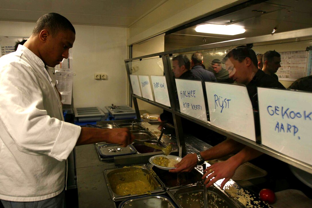 U.S. Marine Lance Cpl. Durrell Rodriguez, a cook with Headquarters and Services Company, 2nd Battalion, 25th Marine Regiment, dishes out rice and curry sauce to a group of British Royal Marines.
