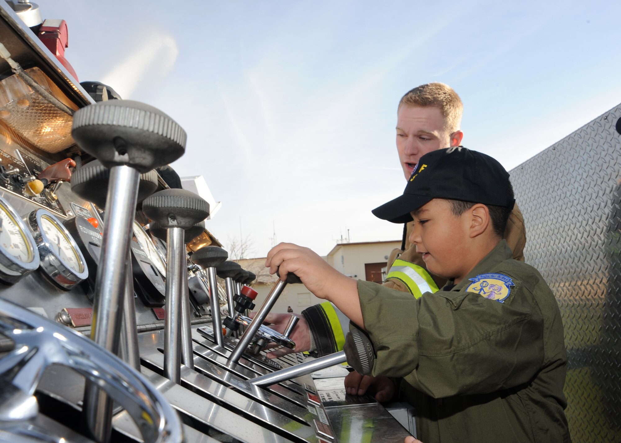 Airman 1st Class David Russell, 355th Civil Engineer Squadron, explains some of the features of the fire truck to Pilot for a Day participant Marcus Lucero, seven years old, at the D-M Fire Department here Feb. 19. Marcus and his family were provided with a tour of the base to include a visit to the 358th Fighter Squadron, the air traffic control tower and the 355th Operations Group, where he had the opportunity to fly in an A-10 simulator. This program affords children with disabilities or serious illnesses with a day devoted to them and their interest in aviation. (U.S. Air Force photo/ Airman Jerilyn Quantanilla) 
