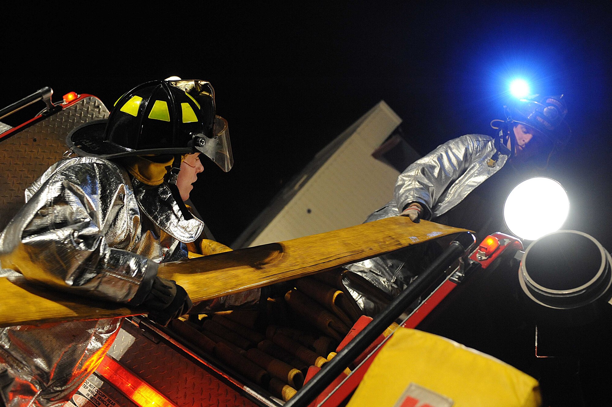ELLSWORTH AIR FORCE BASE S.D.-- (Left) Airman 1st Class Kenneth Colton and Senior Airman John Vasquez, 28th Civil Engineer Squadron firefighters, roll a hose into a fire truck during a night structural fire training exercise Feb. 17. The 28 CES fire department conducts various training scenarios to maintain readiness qualifications. (U.S. Air Force photo/Airman 1st Class Corey Hook)