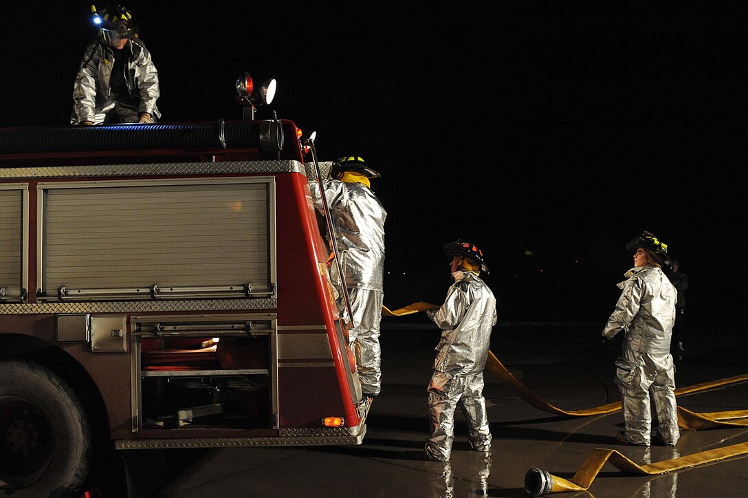 ELLSWORTH AIR FORCE BASE, S.D.-- 28th Civil Engineer Squadron firefighters roll a hose into a fire truck during a night structural fire training exercise, Feb. 17. The simulated structural fires allow firefighters to safely practice extinguishing fires to maintain operational readiness. (US Air Force photo/Airman 1st Class Corey Hook)