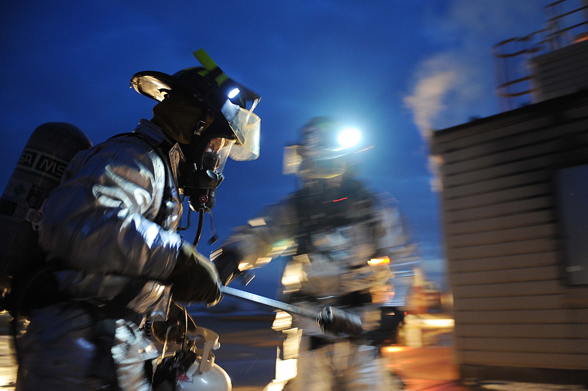 ELLSWORTH AIR FORCE BASE S.D.-- (Left) Senior Airmen Jared Manning and John Vasquez, 28th Civil Engineer Squadron firefighters, go to ignite a fire during a night structural fire training exercise, Feb. 17. The simulated structural fires allow firefighters to safely practice extinguishing fires to maintain operational readiness. (U.S. Air Force photo/Airman 1st Class Corey Hook)