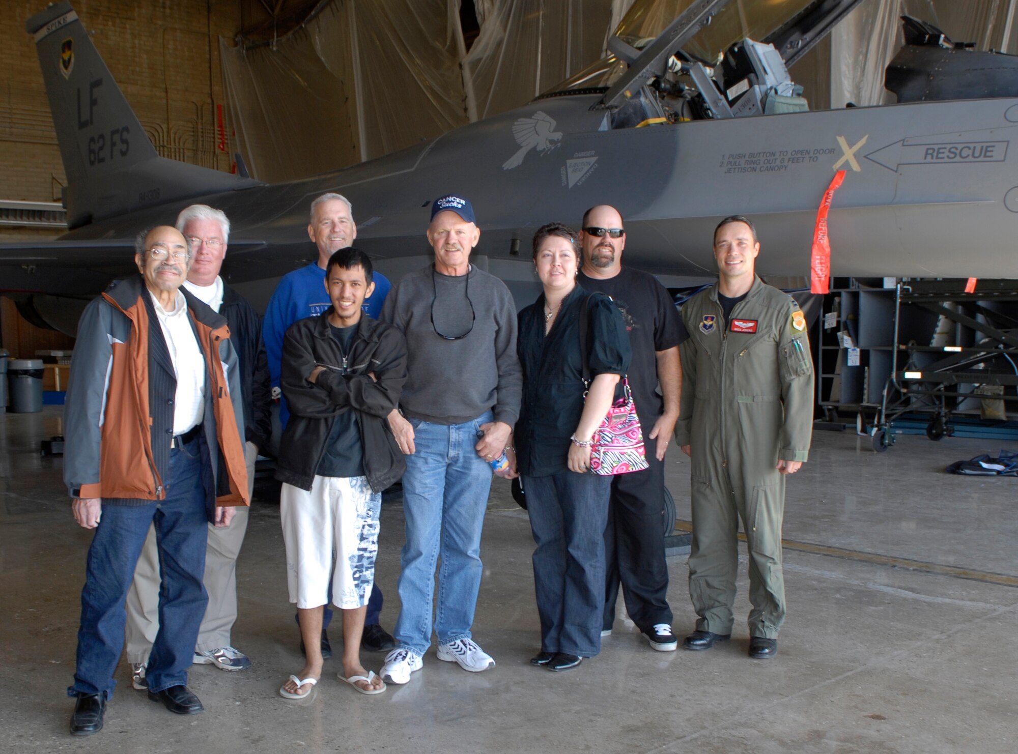 Capt. Gregory Jenkins, an instructor pilot for the 56th Training Squadron, poses for a group photo with patients from the Cancer Treatment Centers of America at Midwestern Regional Medical Center next to an F-16 Fighting Falcon in hangar 450 during a tour Feb. 9.  (U.S. Air Force photo by Airman 1st Class Ronifel Yasay)