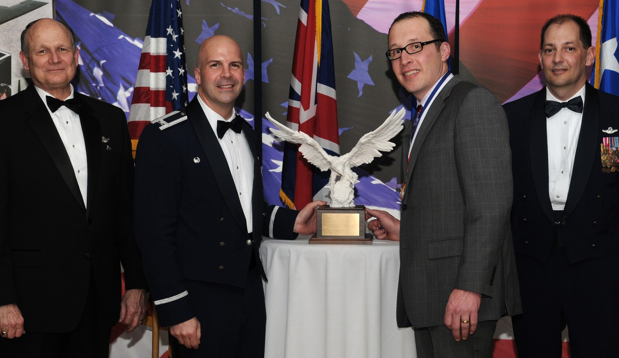 RAF MILDENHALL, England -- Jon Coomber, 727th Air Mobility Squadron passenger service agent, is the Team Mildenhall 2009 Civilian Employee of the Year. His achievements include processing more than 350 troops into and out of Operations Iraqi Freedom and Enduring Freedom. He also supported three missions with 132 U.S. Secret Service personnel and 18 tons of vehicles in support of the 2009 G20 Summit. He is presented this award by retired Gen. Gregory Martin, Col. Chad Manske, 100th Air Refueling Wing commander, and Chief Master Sgt. Antonio Hickey, 100th ARW command chief. (U.S. Air Force photo/Senior Airman Thomas Trower) 