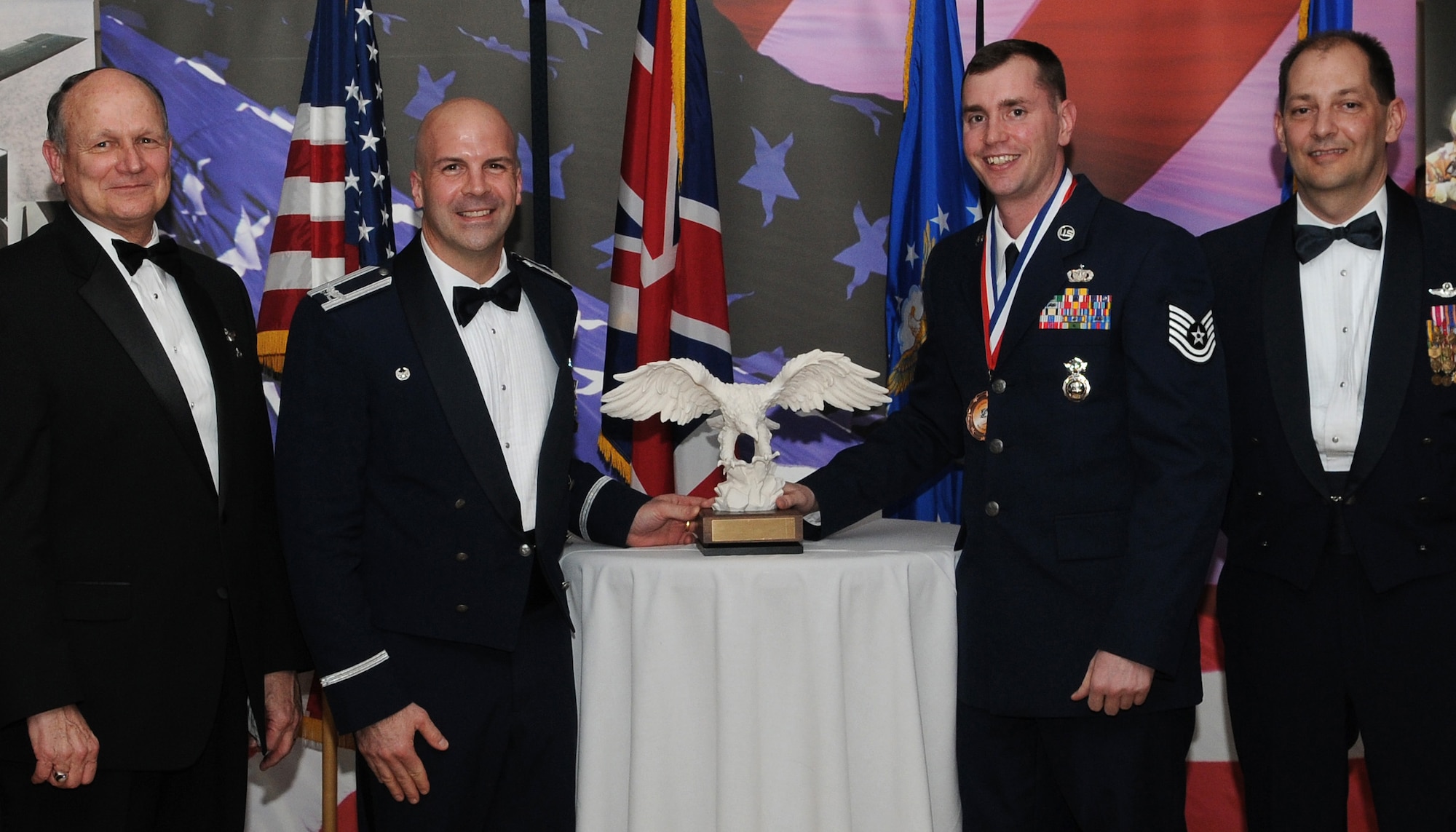 RAF MILDENHALL, England -- Tech. Sgt. Thomas Kazmierski, 100th Security Forces Squadron quality control evaluator, is the 100th Air Refueling Wing 2009 Volunteer of the Year. His volunteer efforts include volunteering more than 225 hours with various events such as Joan Mann Special Sports Day, the 100th SFS Christmas party, the RAF Mildenhall 75th Anniversary Air Show and reading to children at the Child Development Center. He is presented this award by retired Gen. Gregory Martin, Col. Chad Manske, 100th ARW commander, and Chief Master Sgt. Antonio Hickey, 100th ARW command chief. (U.S. Air Force photo/Senior Airman Thomas Trower) 