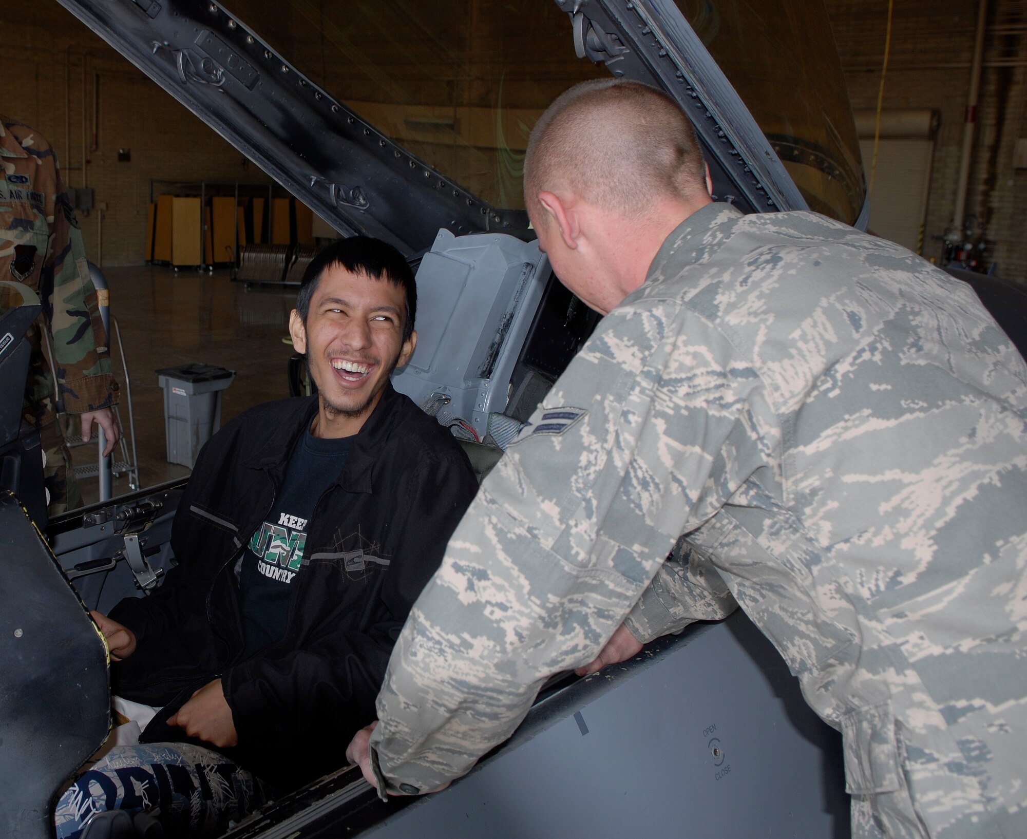 Jarad "Aina" Tezzamos, a Cancer Treatment Centers of America patient at Midwestern Regional Medical Center, shares a laugh with Airman 1st Class Michael McFadden, 62nd Aircraft Maintenance Unit crew chief, Feb. 9 in Hanger 450 during a tour at Luke Air Force Base. Mr. Tezzamos, who goes by his Hawaiian name, Aina, is originally from Hawaii. (U.S. Air Force photo by Airman 1st Class Ronifel Yasay)