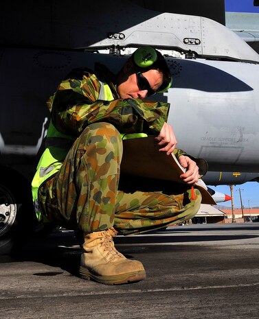 NELLIS AIR FORCE BASE, Nev. -- Air Craftsman Benjamin Cockroft, from the 77th Squadron, Royal Australian Air Force, looks through the aircraft forms before his team mounts a laser-guided training round on an F/A-18 Hornet Feb. 23, the second day of Red Flag 10-3. The airmen from the 77th Squadron are stationed at RAAF Base Williamtown, near Newcastle, Australia. (U.S. Air Force photo by Tech. Sgt. Chris Flahive)