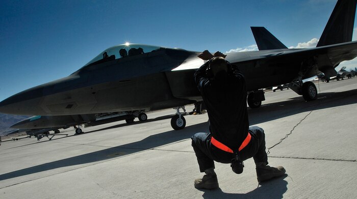 NELLIS AIR FORCE BASE, Nev. -- Airman 1st Class Jeremy Davidson, a crew chief from the 7th Aircraft Maintenance Unit at Holloman AFB, N.M., deployed to Nellis, relays to an F-22 Raptor pilot to hold through marshalling signs before he launches out for a mission on the opening day of Red Flag 10-3 Feb. 22. This is Airman Davidson's first Red Flag and he says he looks forward to learning a lot while he is here. (U.S. Air Force photo by Tech. Sgt. Chris Flahive)
