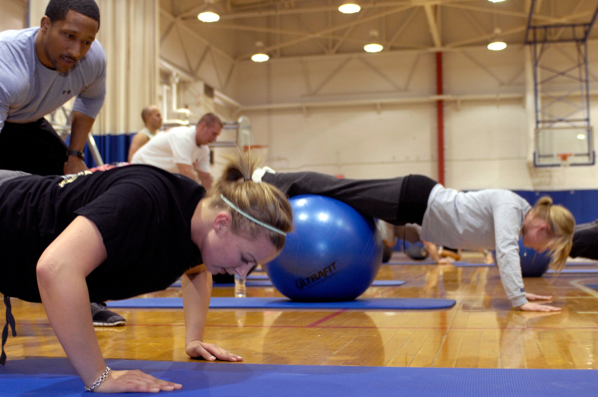 WHITEMAN AIR FORCE BASE, Mo. - Staff Sgt. Raymond Campbell, 509th Medical Operations Squadron, gives pointers to Airman 1st Class Ariel Roness, 509th Combat Training Squadron, as she performs push-ups while using an aerobic ball Feb. 16, 2010, during a P90X workout class now provided at the Whiteman Fitness Center. For more information, call the fitness center at 687-5496. (U.S. Air Force photo/Staff Sgt. Jason Barebo)