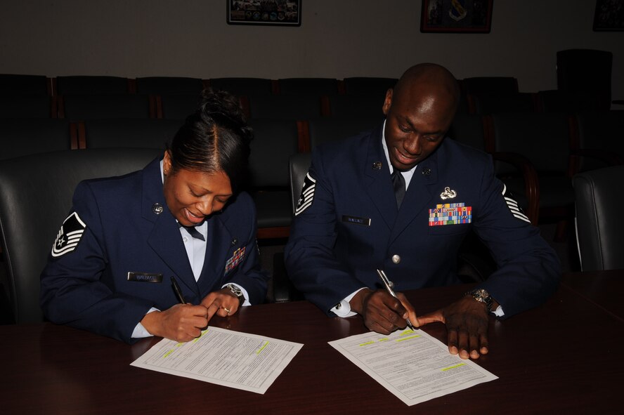 Master Sgts. Ataya Wallace, 4th Fighter Wing Command Section superintendent, and Shaffinie Wallace, 4th Medical Group first sergeant, sign their reenlistment papers in the Thomas Koritz Clinic training room, Feb. 19, 2010. To accept orders to Misawa Air Base, Japan, both Airmen had to reenlist or extend. Ataya hails from Madisonville, Ky, and Shaffinie is from Butler, Ala. (U.S. Air Force photo/Senior Airman Whitney Lambert)