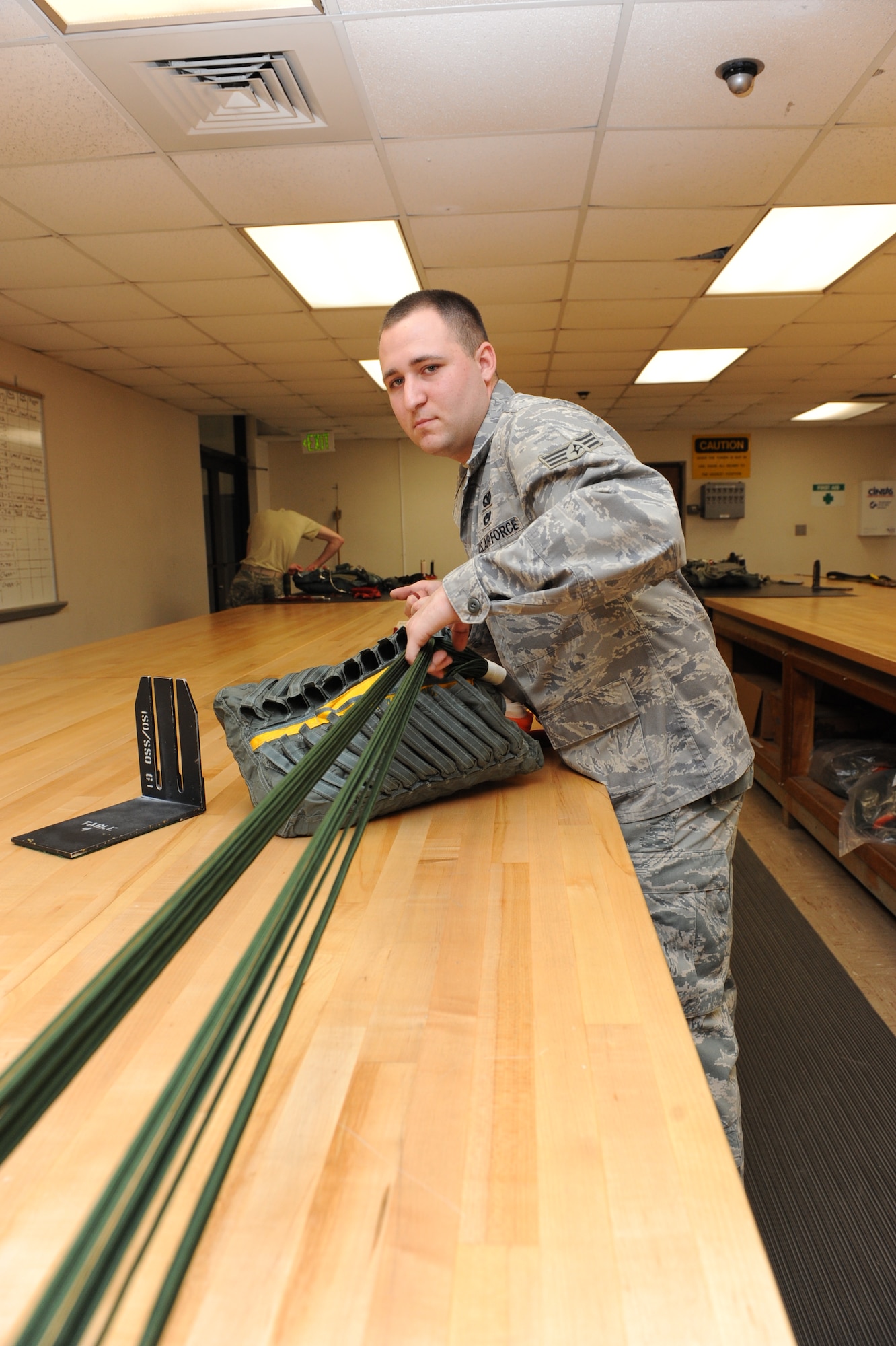 Senior Airman Joshua Peninger, a 19th Operations Support Squadron aircrew flight equipment journeyman, tests the suspension lines of a parachute for any tangles before stowing it into a quarter deployment bag. The bag is one of many pieces of equipment that ensure the safety of the individual during the deployment of a parachute. (U.S. Air Force photo by Senior Airman Ethan Morgan)