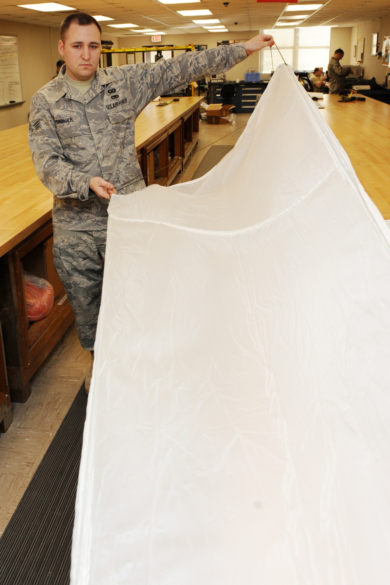 Senior Airman Joshua Peninger, a 19th Operations Support Squadron aircrew flight equipment journeyman, inspects a parachute canopy for holes, rips, tears, dirt and other hazards. When inspected on a regular basis, a parachute has about a 13-year lifespan. (U.S. Air Force photo by Senior Airman Ethan Morgan)