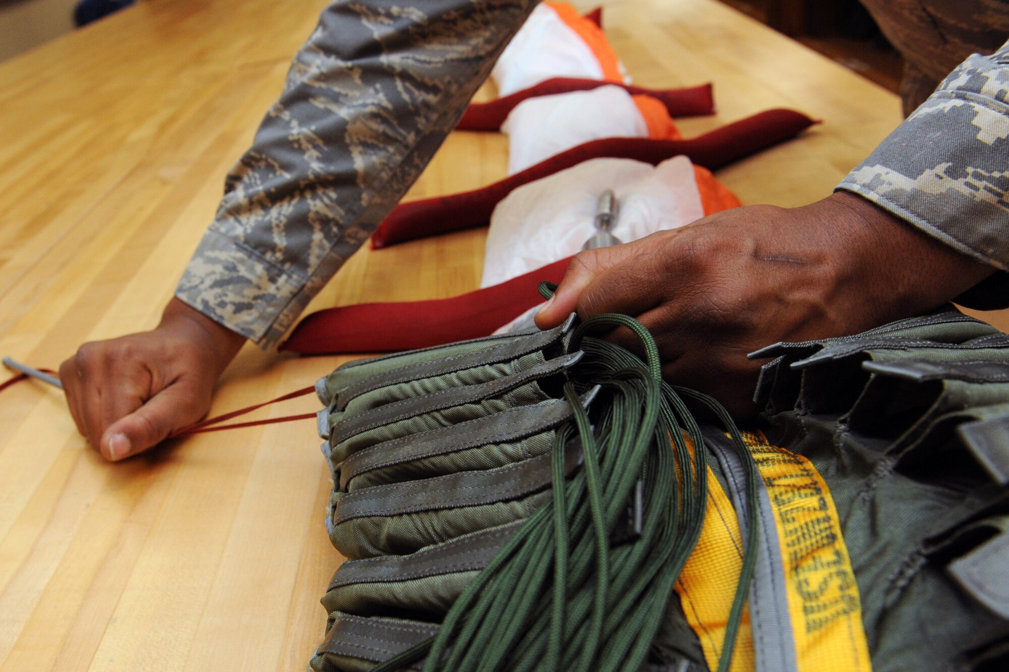 Airman 1st Class Daniel Reaves, a 19th Operations Support Squadron aircrew flight equipment apprentice, stows suspension lines which are attached to the canopy, allowing it to deploy smoothly into a quarter deployment bag used to store the parachute lines and canopy. The bag is one of many pieces of equipment that ensure the safety of the individual during the deployment of a parachute. (U.S. Air Force photo by Senior Airman Ethan Morgan)