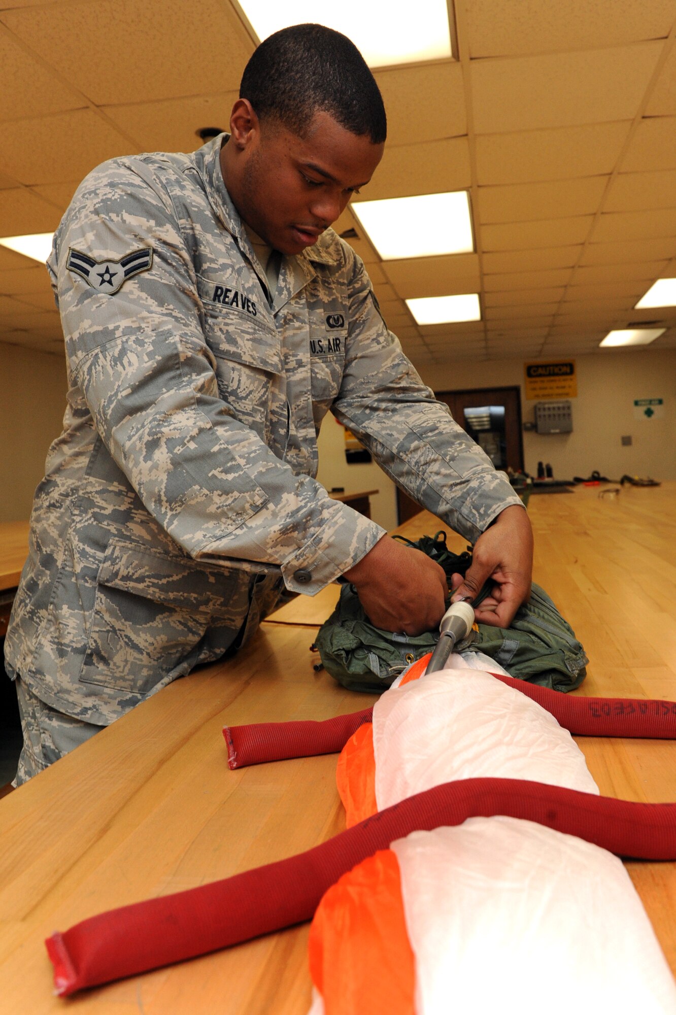 Airman 1st Class Daniel Reaves, a 19th Operations Support Squadron aircrew flight equipment apprentice, stows suspension lines which are attached to the canopy and allow it to deploy smoothly, into a quarter deployment bag used to store the parachute lines and canopy.  The bag helps to keep the parachute lines untangled during deployment. (U.S. Air Force photo by Senior Airman Ethan Morgan)