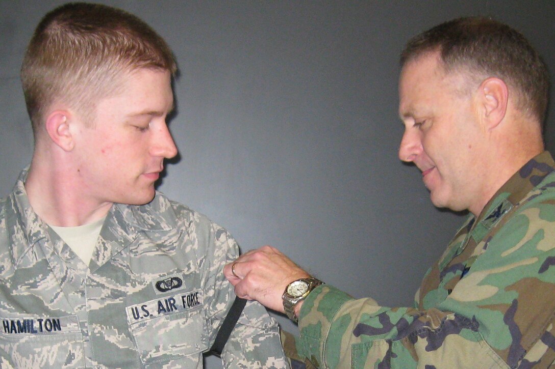 GRISSOM AIR RESERVE BASE, Ind., -- William Hamilton, 434th Air Refueling Wing command post controller, watches intently as Col. Tim Cox, 434th ARW vice commander,  slides Senior Airman stripes onto his uniform. Airman Hamilton was recognized during a wing staff meeting. (U.S. Air Force photo/Senior Airman Carl Berry)
