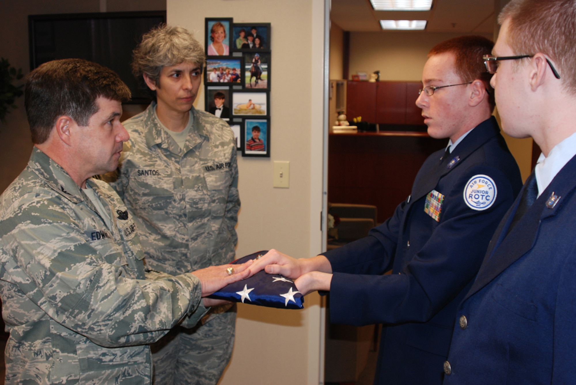 Commander of the 932nd Airlift Wing, Col. William Edwards, Jr., receives a United States flag from Junior Reserve Officer Training Corps Cadet Senior Master Sgt. Patrick Sanders (holding flag) and Cadet Staff Sgt. Nathaniel Signorotti, while
Command Chief Master Sgt. Sandra Santos watches.  The Illinois cadets, from Mascoutah High School near Scott Air Force Base, presented the flag in memory of Tech. Sgt. Anthony Campbell, who died while on duty in Afghanistan.  (U.S. Air Force photo/Maj. Stan Paregien)