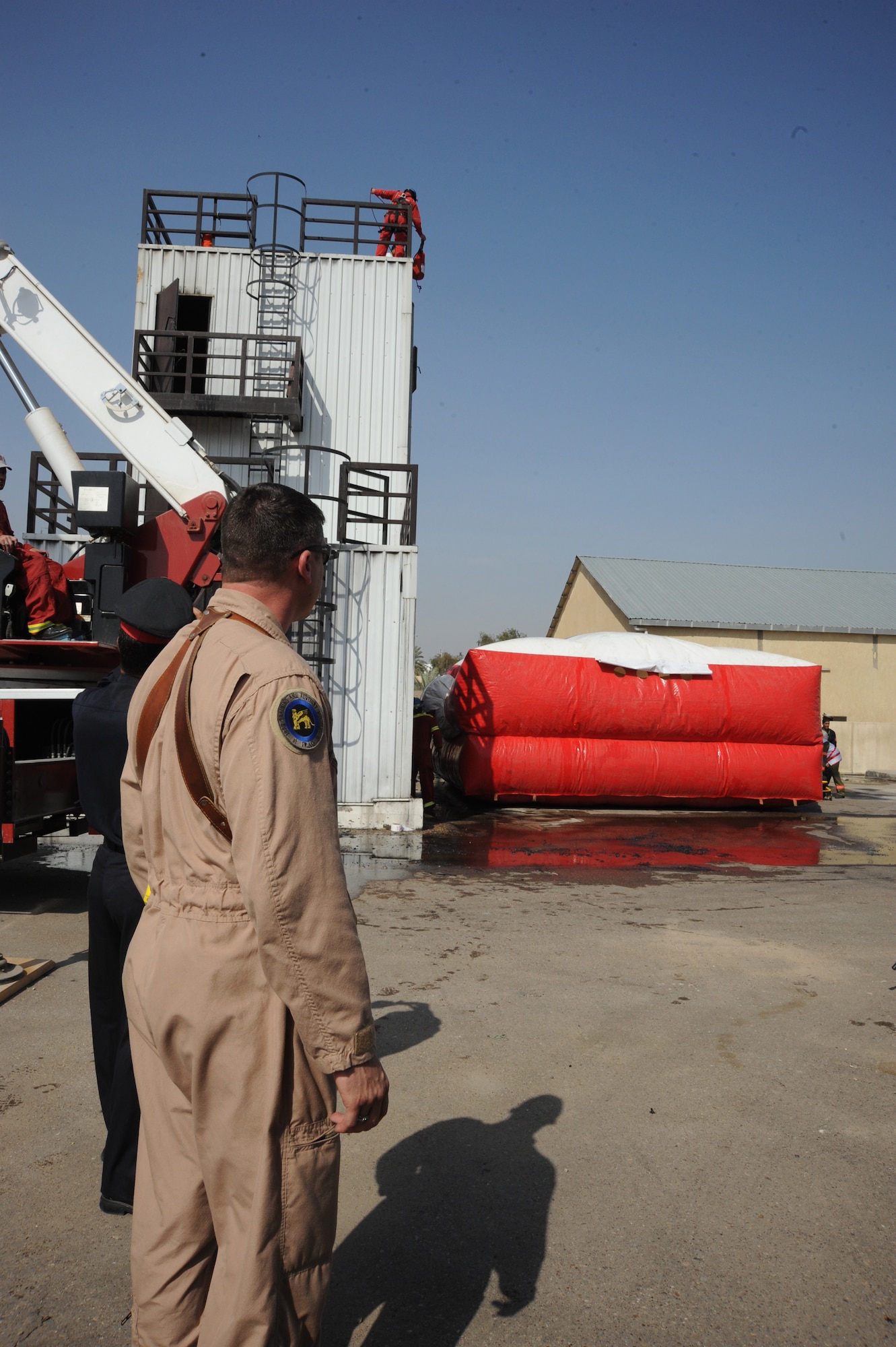 Master Sgt. Jeffrey Kimball, fire rescue advisor for the 821st Expeditionary Training Squadron, oversees an Iraqi Civil Defense Department firefighter jumping on to an air bag during a demonstration in Baghdad, Iraq, Feb. 17, 2010. The Iraqi Civil Defense Training Academy is currently working to establish an internationally accepted based curriculum; the future vision of the academy is to become internationally certified and become one of the premier fire training institutions in the Middle East. (U.S. Air Force photo/Master Sgt. Trish Bunting/Released)