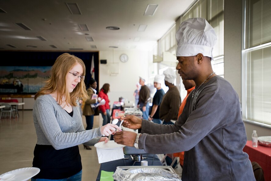MISAWA AIR BASE, Japan -- Tech. Sgt. Andre Moore, 35th Force Support Squadron eligibility NCO in charge, serves a helping of Carribbean-chick peas to Senior Airman Tiffany Mandrell, 35th Comptroller Squadron budget analyst, during the Misawa Men Who Cook competition Feb. 20 at Sollars Elementary School. Sergeant Moore won the "Best in Show" award with his Caribbean-curry chicken. (U.S. Air Force photo/Senior Airman Jamal D. Sutter)